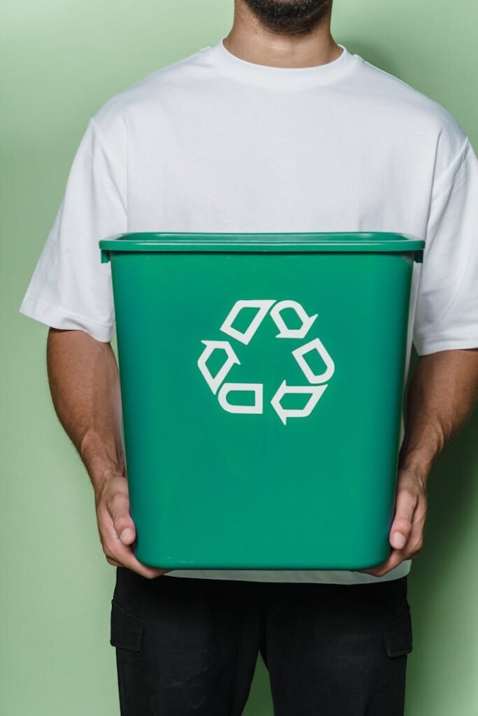 Crafting Captivating Headlines: Your awesome post title goes here Adult male holding a green recycling bin against a green background, promoting sustainability.